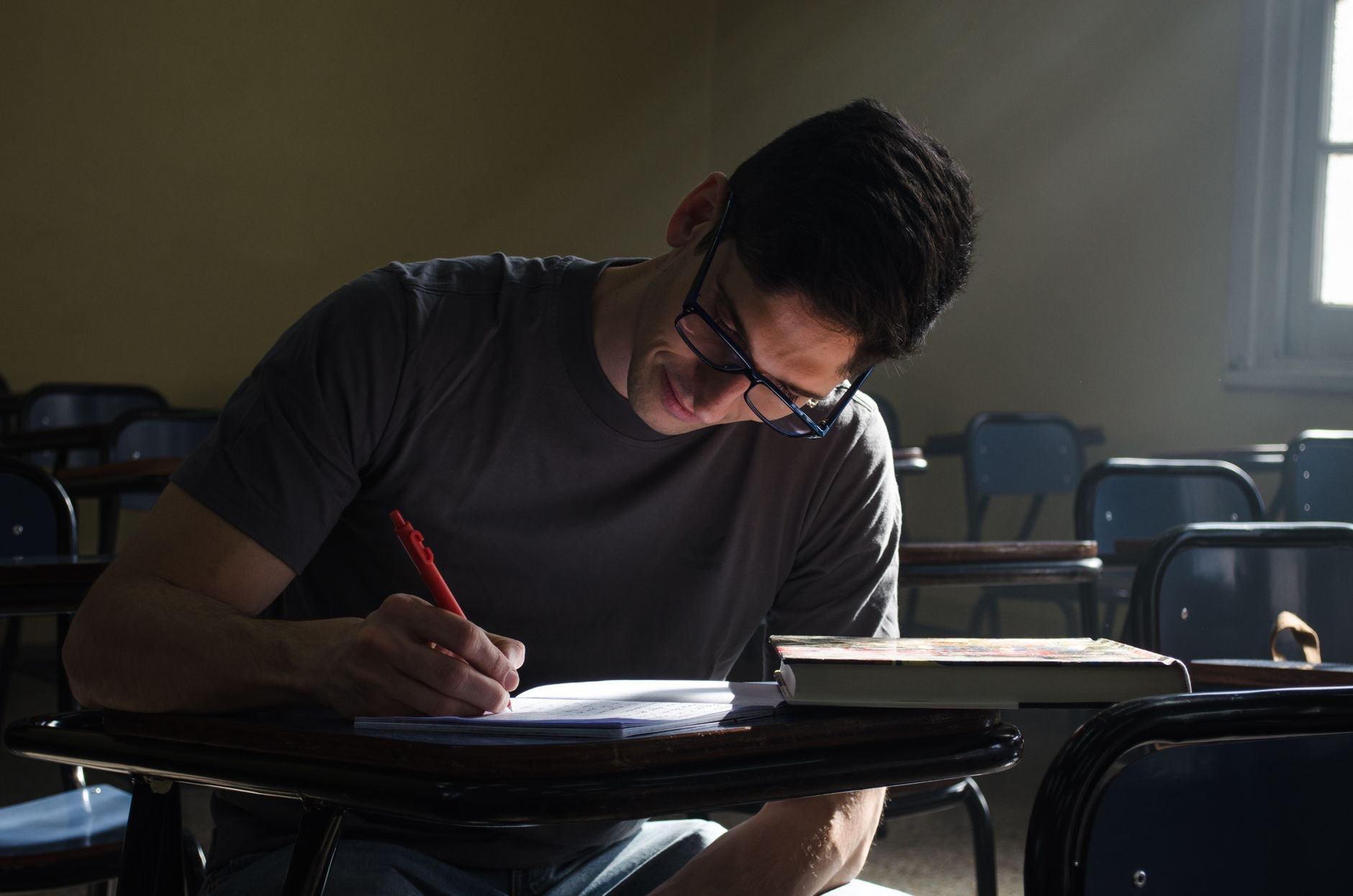 Young man studying and writing notes, focused and deliberate