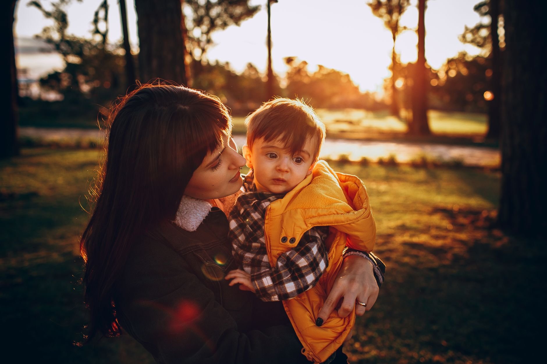 A mother lovingly holds her child outdoors in warm golden light